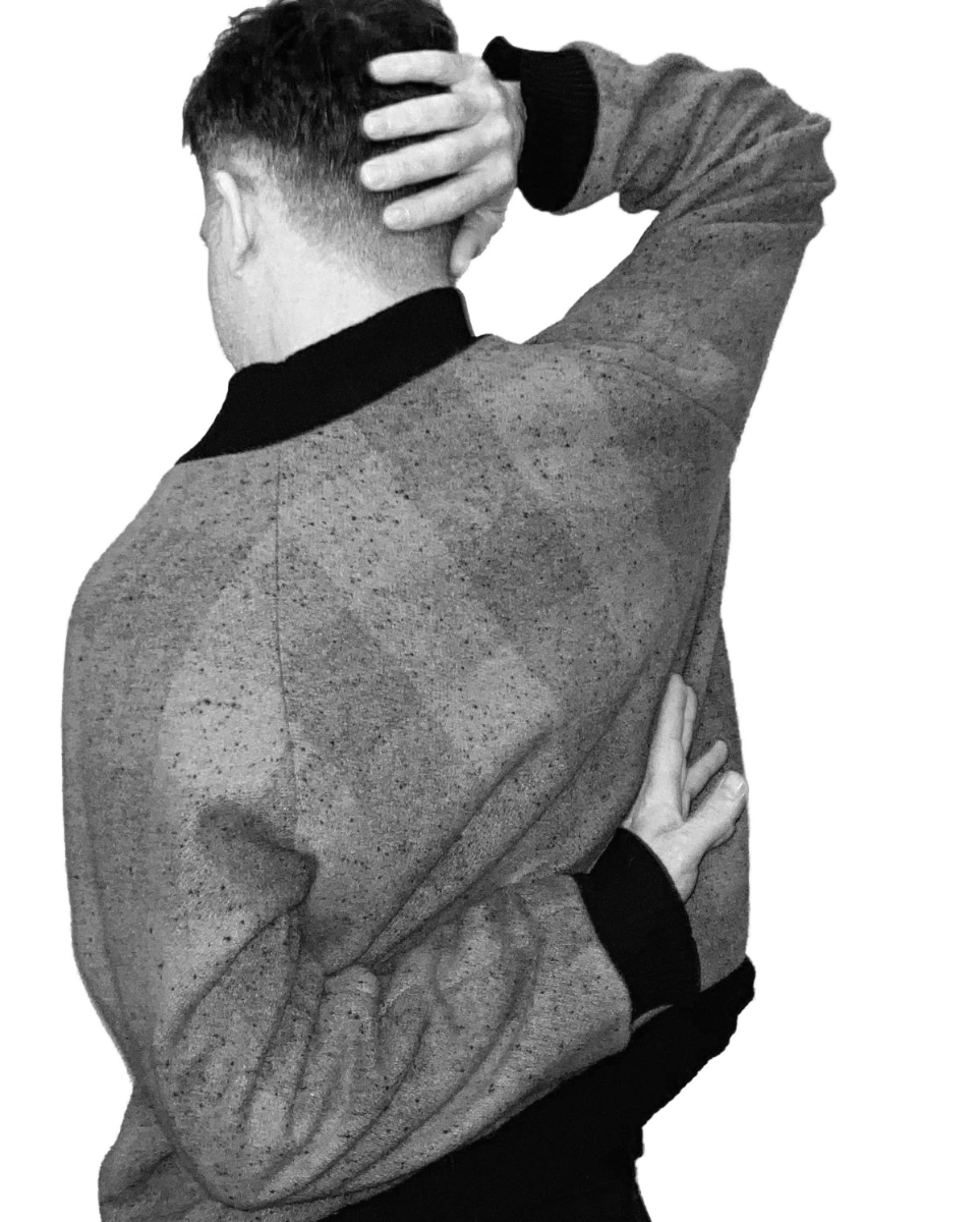 Photo of a man in checked wool coat from behind with arms folded above and below.